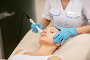 Dermatologist touching face of client while doing skin tightening - obrazy, fototapety, plakaty