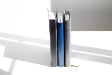 the three books stand in a row of blue black and gray on a white background with a shadow view from above