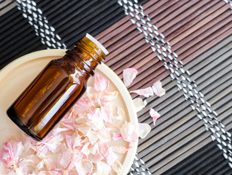 Small Bottle With Essential Oil On The Small Plate With Dry Pink Geranium Flowers. Background With Dried Flowers Petals. Aromatherapy, Spa And Herbal Medicine Concept. Copy Space, Top View.