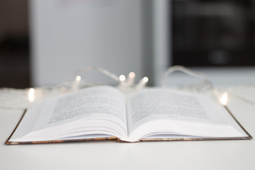 open book sheets fan on white background bokeh garland closeup