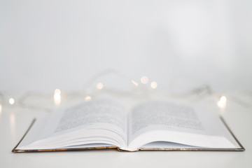 open book sheets fan on white background bokeh garland closeup