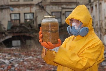Man with protective  mask and protective clothes explores danger jar.