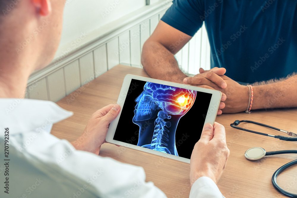 Wall mural doctor holding a digital tablet with x-ray of the 3d head of the patient with pain on the back of th