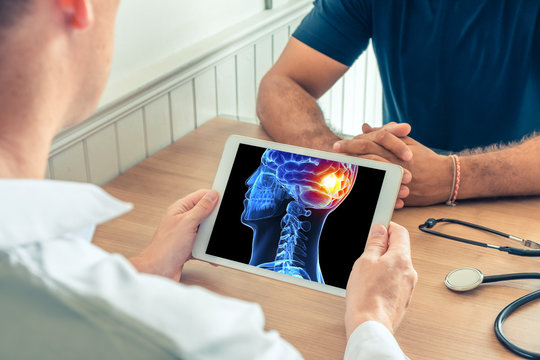 Doctor holding a digital tablet with x-ray of the 3D head of the patient with pain on the back of the brain.