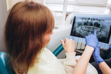 family house dentist shows an x-ray. a young woman sitting at a reception near a dentist. Girl dentist