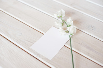 Wedding invitation birthday gift certificate for a spa or care decorated letter card on a white wooden table with a branch of white flowers.