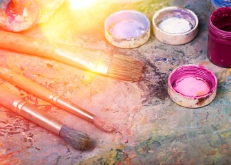 Artist paints a picture of oil paint brush in hand with palette closeup