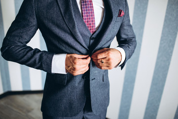 stylish groomsmen helping happy groom getting ready in the morning for wedding ceremony. luxury man in suit in room. wedding day.