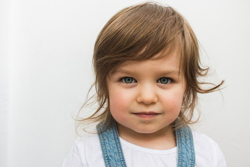 Beautiful blonde Caucasian toddler child with blue eyes closeup portrait. Calm and serious attentive girl on isolated background