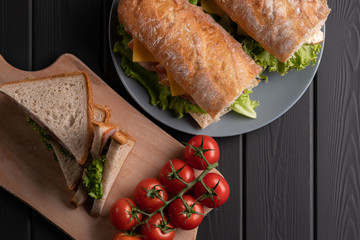 Fresh delicious baguette and sandwich on black background. Bread lunch. Healthy dinner