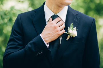 stylish groomsmen helping happy groom getting ready in the morning for wedding ceremony. luxury man in suit in room. wedding day.