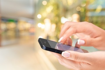 Hand holding smartphone on supermarket bokeh background