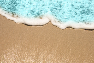 Soft wave of turquoise sea water on the sandy beach.
