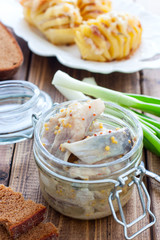 Herring marinated in mustard pieces in a glass jar, selective focus