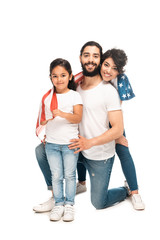 cheerful latin family smiling while holding american flag isolated on white