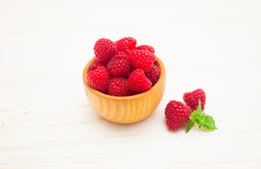 Bowl with ripe aromatic raspberries on wooden table