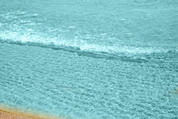 Soft wave of turquoise sea water on the sandy beach