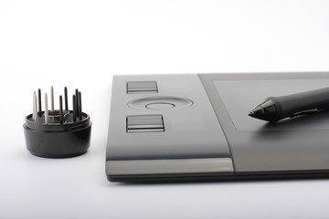 A close-up of  pen on graphic tablet and nibs on stand