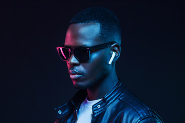 Neon portrait of African American man wearing wireless earphones and leather jacket