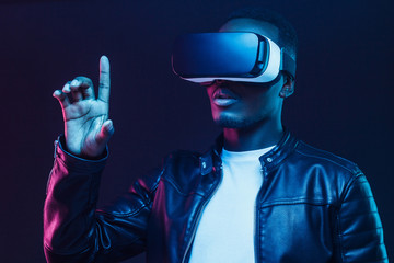 African american man in vr glasses, using virtual reality headset, trying to touch something with finger