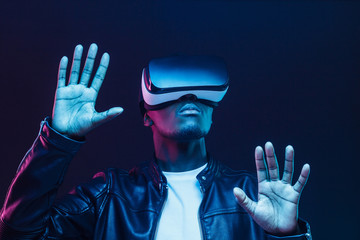 African man in vr glasses, playing video games with virtual reality headset, trying to touch...