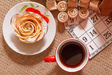 Cup of coffee and homemade biscuit with board game lotto on sackcloth.