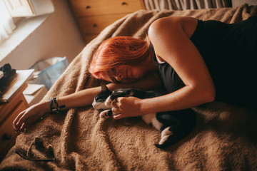 redhead woman lying on the bed stroking a kitten