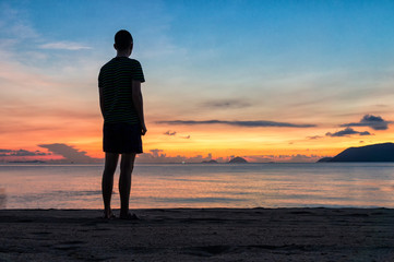Fototapeta premium Silhouettes of man on beach at a colorful sunrise with amazing sky over ocean