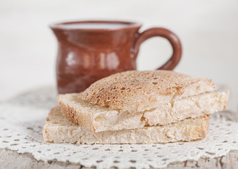 Slices of fresh bread and Cup of milk on the old table