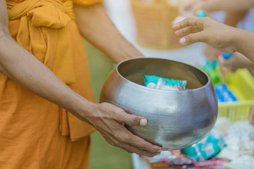 Teachers and students together make merit to give food offerings to a Buddhist monk on important religious days at school.