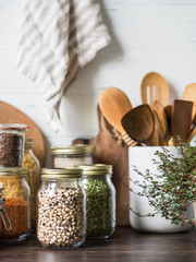 Various cereals and seeds - peas, beans, rice, pasta, flax, lentils in glass jars on the table in...