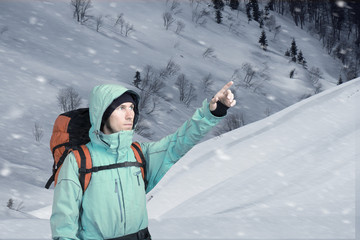 Portrait of adventurous young man on winter mountainside view pointing out. Active lifestyle and...