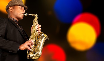 Obraz premium Close-up man playing on saxophone on blurred background