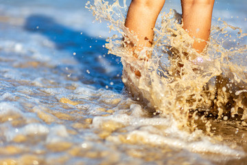 Sea foam, waves and naked feet on a sand beach. Holidays, relax, summer background 