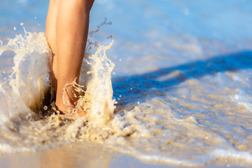 Sea foam, waves and naked feet on a sand beach. Holidays, relax, summer background 