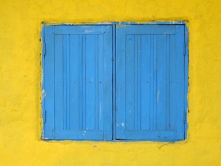 old blue wood window close on yellow wall