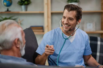 Fototapeta premium Happy doctor gesturing while talking to a senior patient during a home visit.