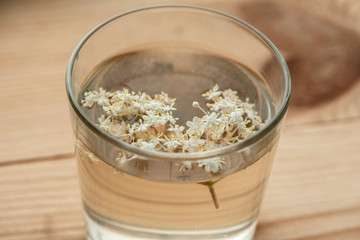 Infusion of elderberry flowers in a glass on the table.