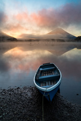 Beautiful mystical sunrise at Lake Shōji with Mount Fuji as a backdrop and a row boat in the foreground - obrazy, fototapety, plakaty
