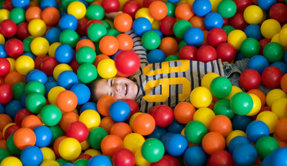 boy having fun in pool with colorful balls