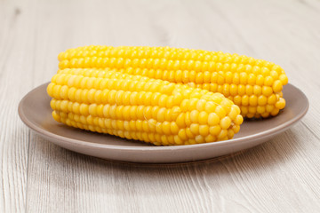 Porcelain plate with boiled corn on a table.