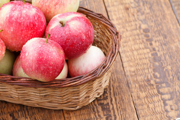 Red apples in the wicker basket on wooden boards