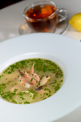 seafood soup in a white plate decorated with shrimps