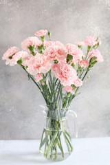 gentle pink carnation flowers in vase on grey background 