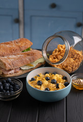 Delicious fresh food. Breakfast. Corn flakes with fruit and honey. Tasty italian baguette, sandwich on black background. Traditional meal