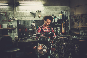 African american woman mechanic repairing a motorcycle in a workshop