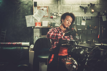 African american woman mechanic repairing a motorcycle in a workshop