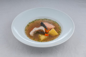 fish soup in atorsky serve from the chef on a white plate on a white background