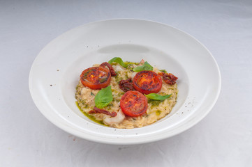 seafood risotto and dried tomatoes on a white plate on a white background