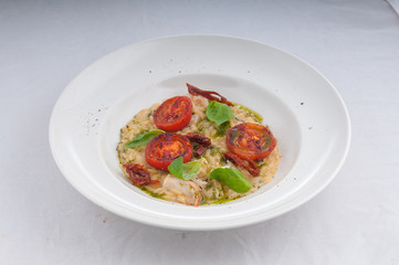 seafood risotto and dried tomatoes on a white plate on a white background